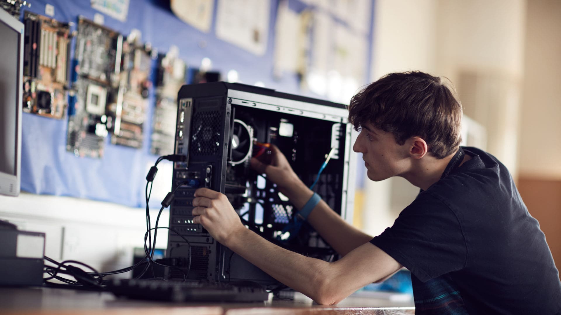 鶹 student focusing on fixing a computer on an IT course